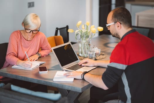 Adult caucasian couple working from home a couple days a week. Adult person working from home, from different rooms in the house, in the kitchen, dining room, office.