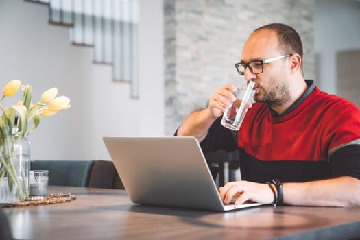 Adult caucasian man working from home a couple days a week. Adult person working from home, from different rooms in the house, in the kitchen, dining room, office.