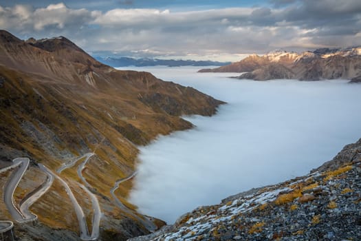 Stelvio pass, mountain dramatic landscape at dawn above mist, Northern Italy