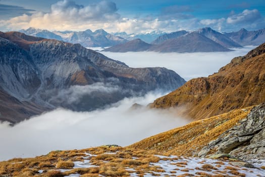 Stelvio pass, mountain dramatic landscape at dawn above mist, Northern Italy