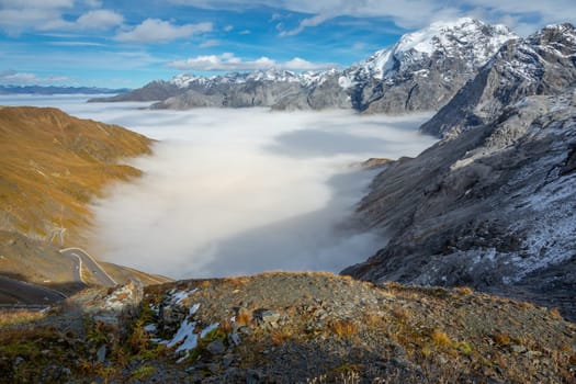 Stelvio pass, mountain dramatic landscape at dawn above mist, Northern Italy