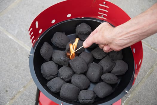 a man lights a fire with a lighter special charcoals for a barbecue a barbecue house on the terrace prepares a place for a barbecue. High quality photo