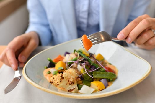 Woman eating fish with vegetables in a restaurant