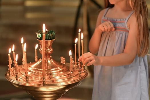 little girl puts a candle in church. Orthodoxy and children