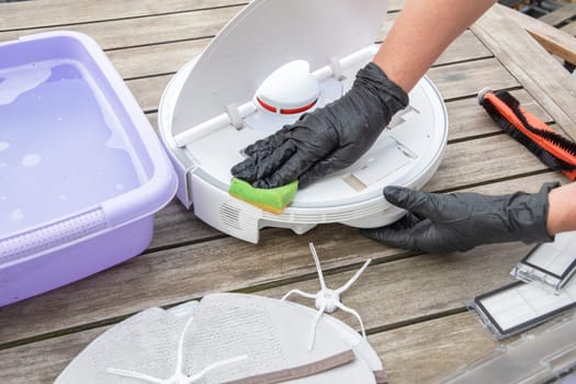 woman washing a trash can in a robot vacuum cleaner,planned maintenance of equipment for long-term use, High quality photo