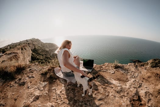 Woman sea laptop. Business woman in yellow hat working on laptop by sea. Close up on hands of pretty lady typing on computer outdoors summer day. Freelance, digital nomad, travel and holidays concept.