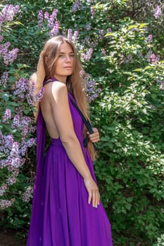 portrait of young woman with long hair outdoors in blooming lilac garden.