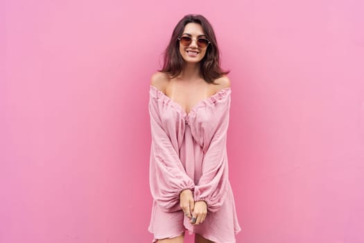 Young beautiful smiling cute romantic woman in trendy summer dress. Carefree woman posing in the street near pink wall. Positive model outdoors in sunglasses. Cheerful and happy.