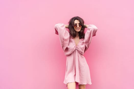 Young beautiful smiling cute romantic woman in trendy summer dress. Carefree woman posing in the street near pink wall. Positive model outdoors in sunglasses. Cheerful and happy.