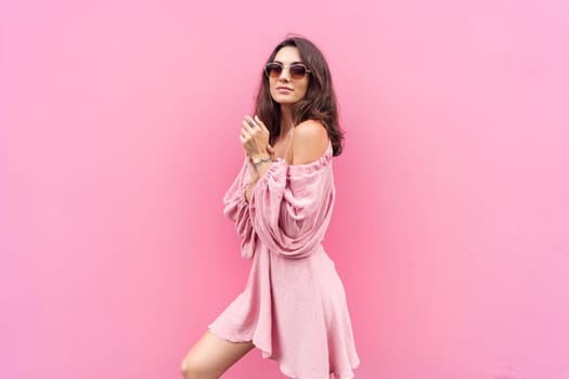 Young beautiful smiling cute romantic woman in trendy summer dress. Carefree woman posing in the street near pink wall. Positive model outdoors in sunglasses. Cheerful and happy.