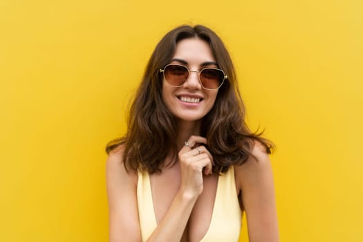 Young beautiful woman. Carefree woman posing in the street near yellow wall. Positive model outdoors in sunglasses. Happy and cheerful