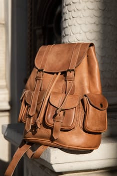 photo of a light brown, retro look leather backpack near column