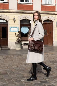 Street style, autumn, spring fashion concept: fashionable woman wearing luxury beige coat, black leggings, ankle bots