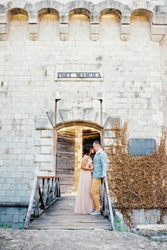 Bride and groom stand together holding hands on the bridge to Mamula Fort. High quality photo