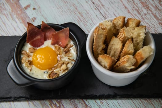 Recipe Oeuf cocotte with fresh cream sauce, Roquefort and walnuts, ham chips, toasted bread sticks. High quality photo