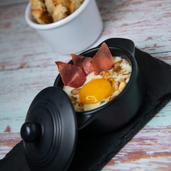 Recipe Oeuf cocotte with fresh cream sauce, Roquefort and walnuts, ham chips, toasted bread sticks. High quality photo