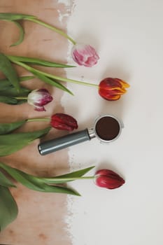 Fresh tulips and metal holder from the coffee machine with ground coffee inside. Coffee horn and flowers