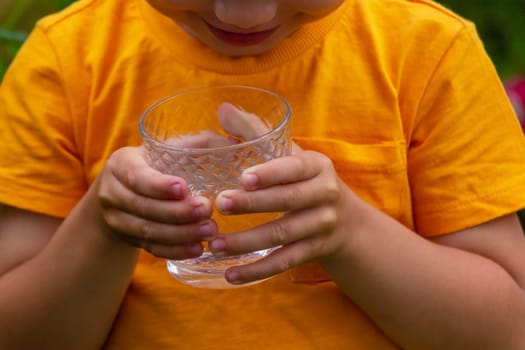 The child drinks water from a glass. Selective focus. Kid.