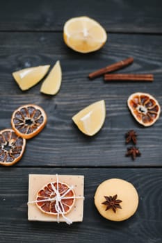 Colored handmade soap with natural ingredients, dried oranges and spies on black wooden background