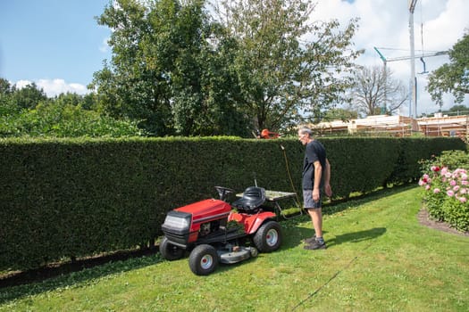 Male gardener using a lawn mowing tractor for cutting grass, professional gardening tools, High quality photo