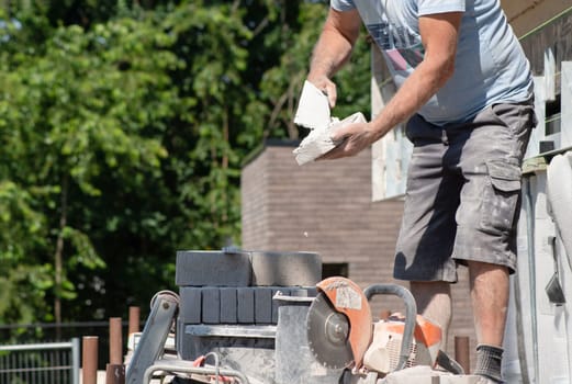 the bricklayer makes the facade of the house from gray bricks with cement and plaster at the construction site. High quality photo