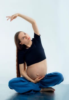 Pleasant pregnant woman posing in profile and trying yoga Young happy expectant relaxing, thinking about her baby and enjoying her future life. Motherhood, pregnancy, yoga concept, lotus position.