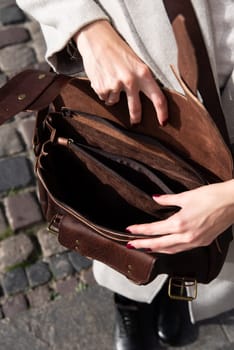 photo of a woman opening a brown leather briefcase with antique and retro look.