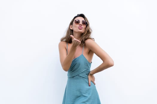 Portrait of beautiful woman in green fitting summer dress on white background natural day light, wearing sunglasses, smiling excited