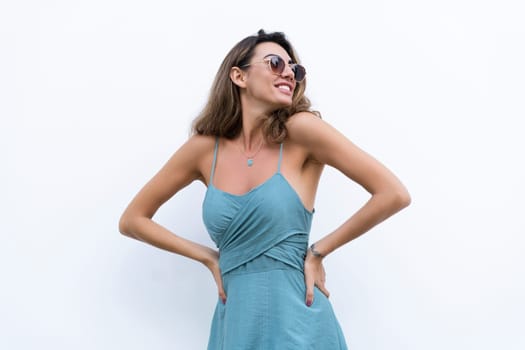 Portrait of beautiful woman in green fitting summer dress on white background natural day light, wearing sunglasses, smiling excited