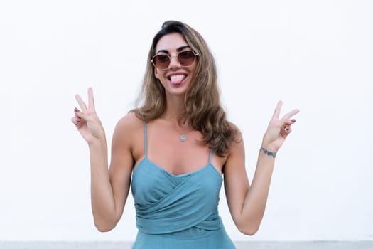 Portrait of beautiful woman in green fitting summer dress on white background natural day light, wearing sunglasses, smiling excited