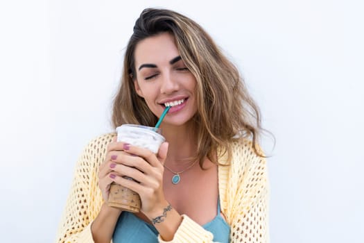 Portrait of beautiful woman in green summer dress on white background natural daylight, holding iced coffee cappuccino happy smiling excited