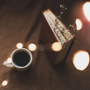 Coffee cup, book, flowers on dark background. Reading, relaxing concept