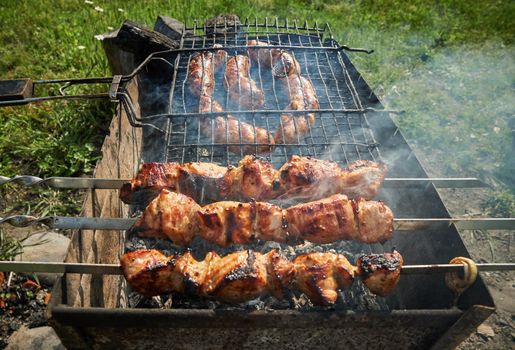 Man preparing shashlik or shish kebab over charcoal. Barbeque meat and sausages or bratwurst on a grill grate in backyard. Grilled meat on metal skewer outdoor. BBQ party or picnic food. Close up shot