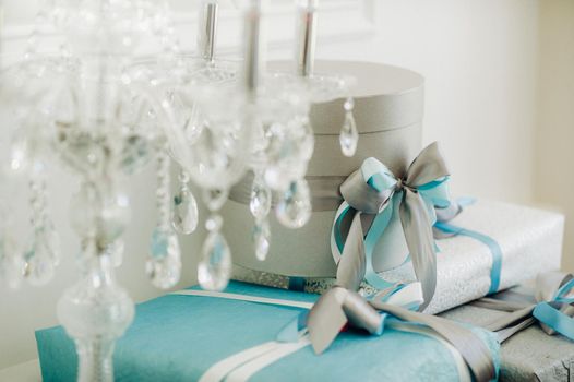 Boxes with gifts Packed in blue and silver paper are on the shelf.