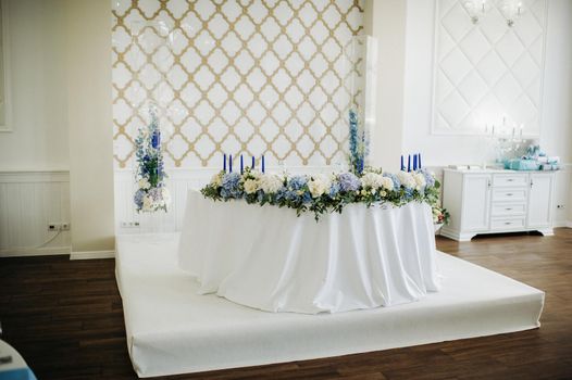 Wedding bride and groom table presidium decorated with a lot of flowers.