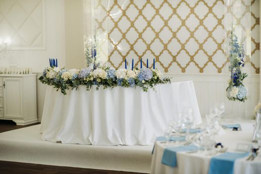 Wedding bride and groom table presidium decorated with a lot of flowers.