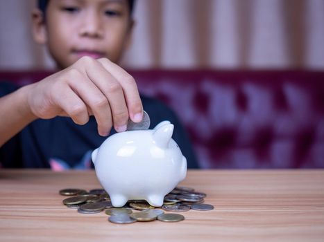 Boy saving money in a white pig piggy bank.Saving concept. Saving for the future.