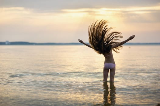 girl with loose hair on the sea during sunset.