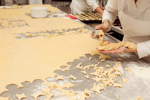 a girl makes cookie molds from a large piece of dough in a bakery.