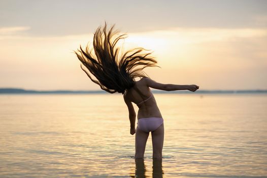 girl with loose hair on the sea during sunset.