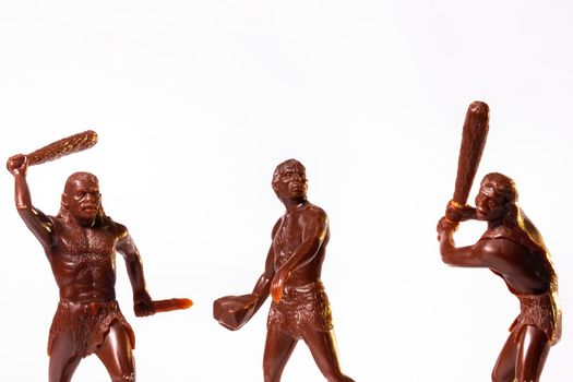 Large toy figures of primitive people on a white background.