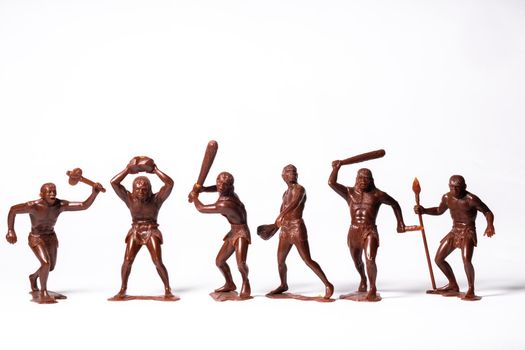 Large toy figures of primitive people on a white background.