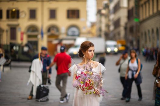 a bride in a wedding dress with a Venetian mask in her hands in Florence.Italy.