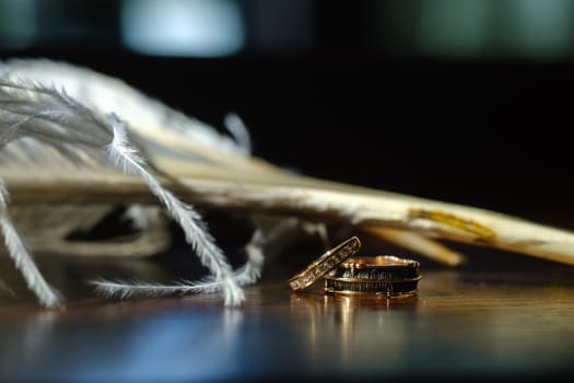 Two wedding rings lie in white feathers. The concept of love.