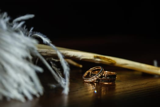 Two wedding rings lie in white feathers. The concept of love.