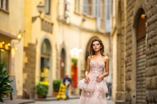 A bride in a pink wedding dress walks in Florence, Italy.