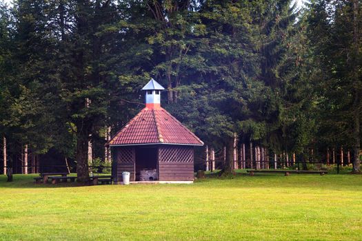 View of barbeque house on grass in front the trees