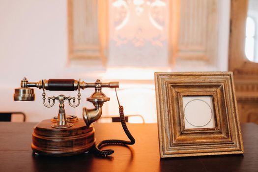 an old retro phone stands next to an empty photo frame.Vintage phone and photo frame.