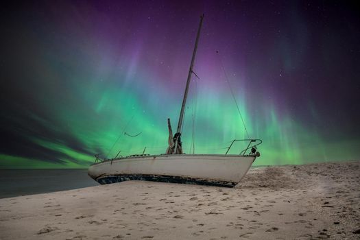 Aurora borealis over a shipwreck off the coast of Uttakleiv Beach in Norway