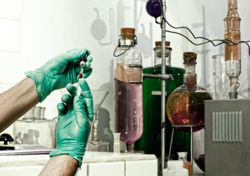 Hands of the doctors with green gloves filling a syringe